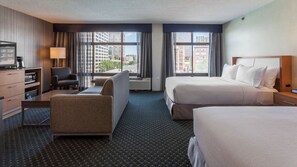 Habitación de hotel con cama, escritorio, silla, televisión y vistas a la ciudad.