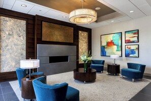 A lobby with a seating area, a large flat-screen TV, artwork on the walls, and a chandelier. - Holiday Inn Chicago North-Evanston by IHG (Evanston)