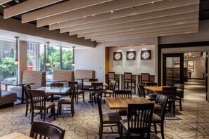 A modern restaurant interior with high ceilings, patterned flooring, and a mix of seating options including booths and tables. - Holiday Inn Chicago North-Evanston by IHG (Evanston)
