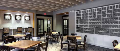 A restaurant interior with multiple tables and chairs, a wall of hanging jars, and clocks on the wall.
