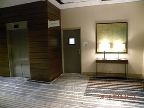 A hotel lobby with two elevators, a reception desk with a lamp, and a sign indicating 'Elevators'. - Holiday Inn Chicago North-Evanston by IHG (Evanston)