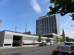 A modern building with a large glass facade, a parking garage entrance, and a church spire in the background. - Holiday Inn Chicago North-Evanston by IHG (Evanston)