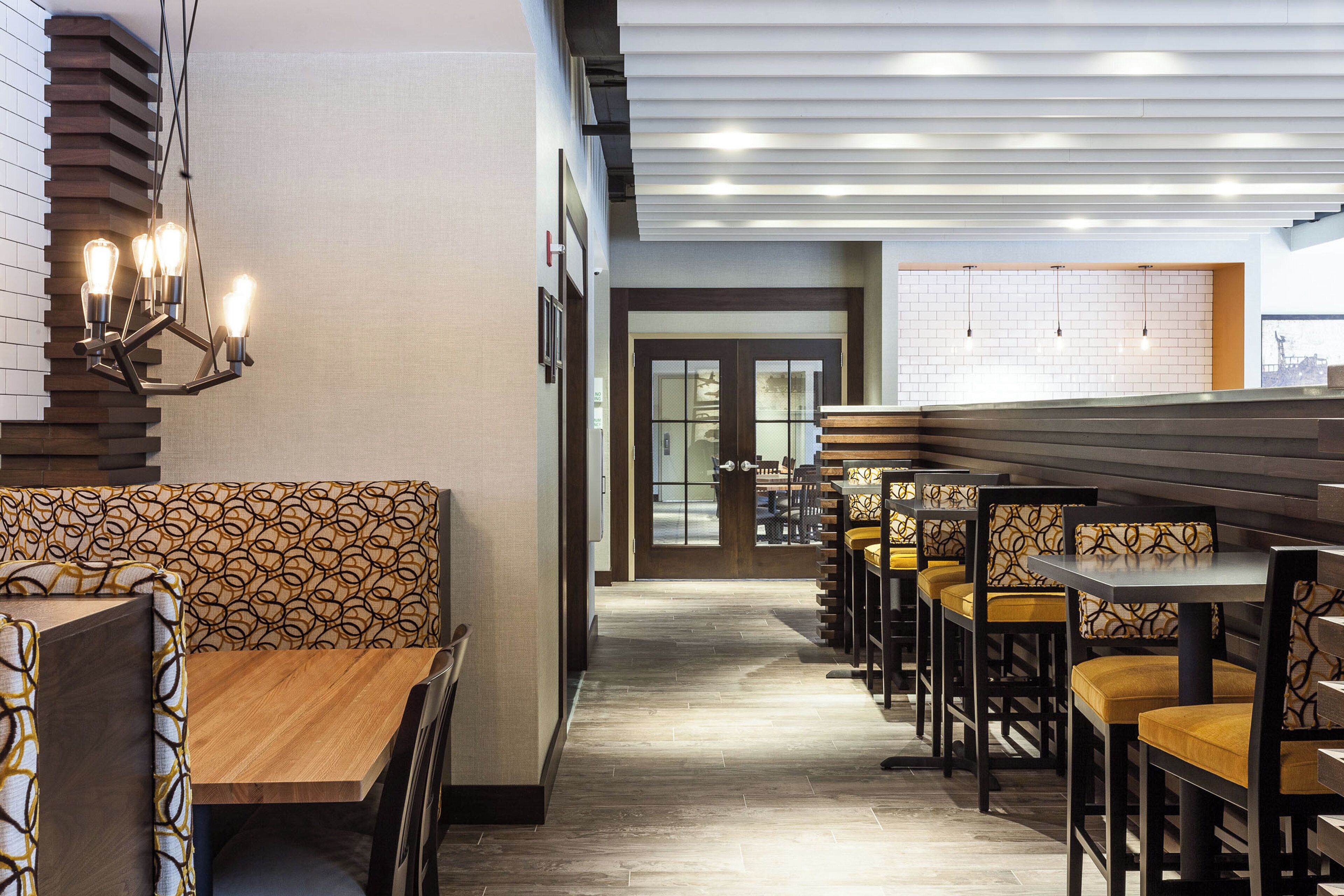A restaurant interior with wooden benches, tables, and a patterned wall.