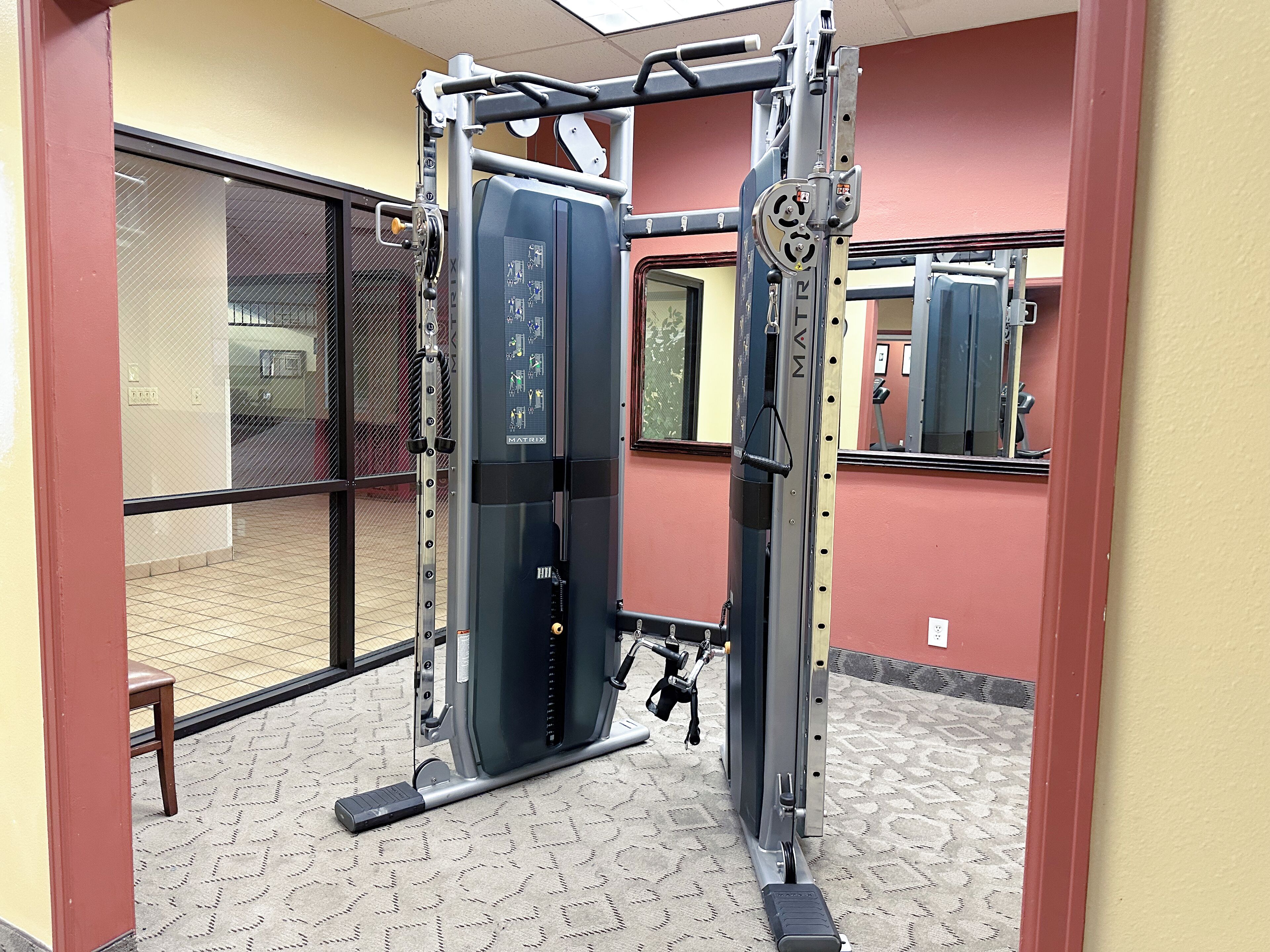 A gym with a pull-up bar, a weight stack, and a mirror.