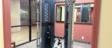 A gym with a pull-up bar, a weight stack, and a mirror.