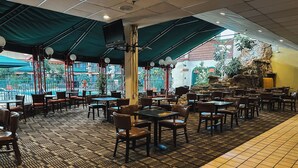 An indoor restaurant with a patterned floor, tables, and chairs. - Clarion Inn (Fort Collins)