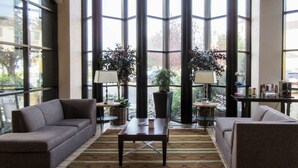 A spacious lobby with two sofas, a coffee table, and potted plants. - Clarion Inn (Fort Collins)