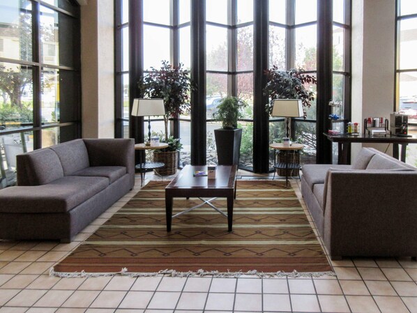A spacious lobby with two sofas, a coffee table, and potted plants.