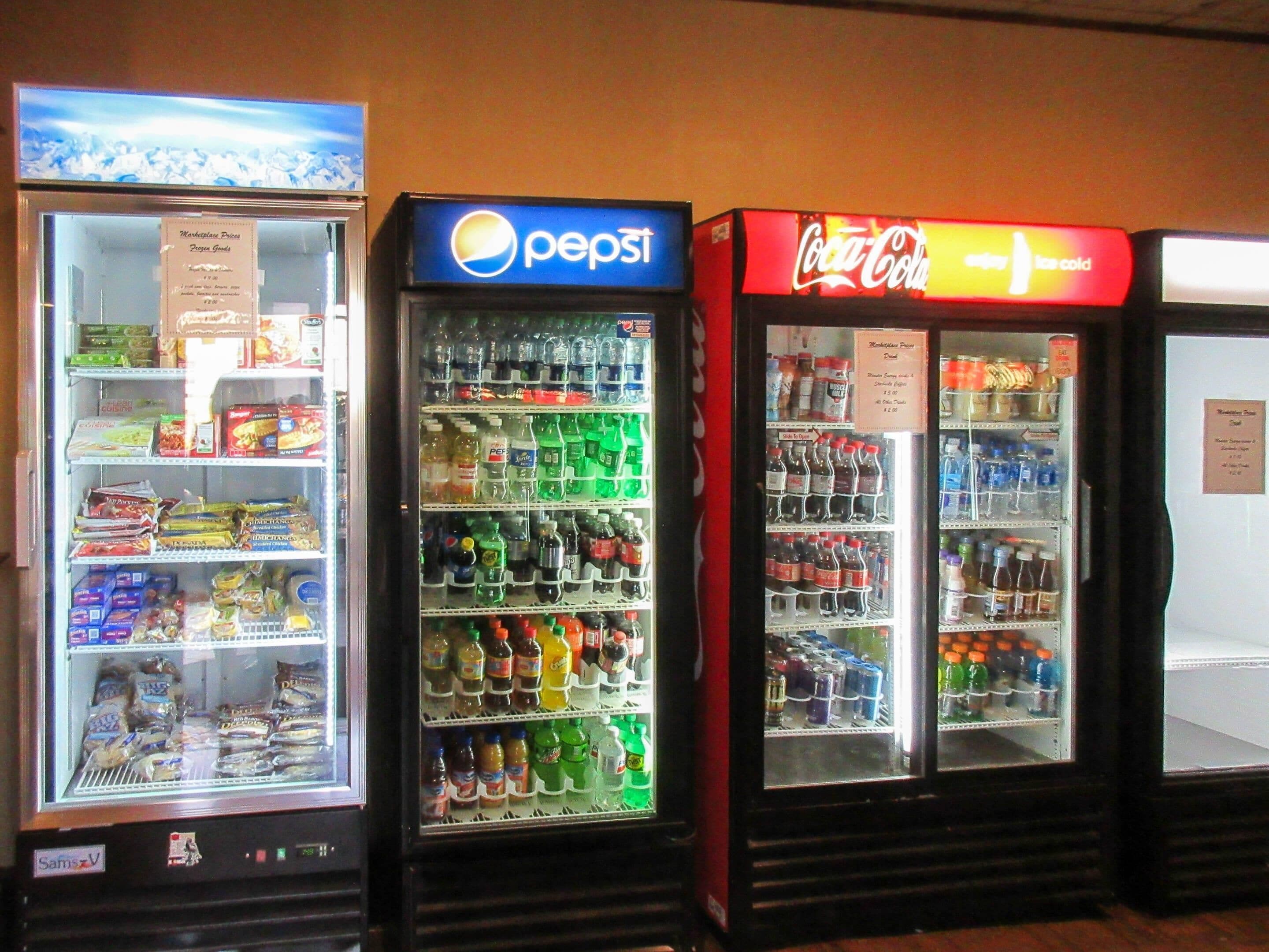 Three beverage vending machines with Pepsi, Coca-Cola, and other drinks.