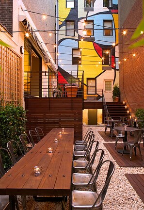 A wooden table with chairs and string lights in an outdoor dining area. - Pod 51 (New York)