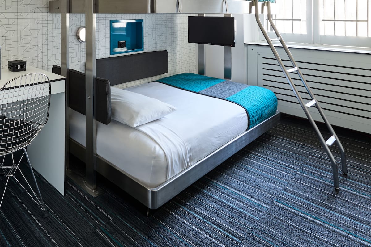 A bunk bed room with a ladder, a desk, and a chair.