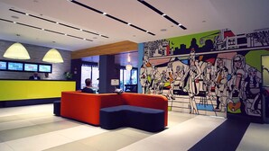 A modern reception area with a colorful mural, a seating area, and a digital information display.