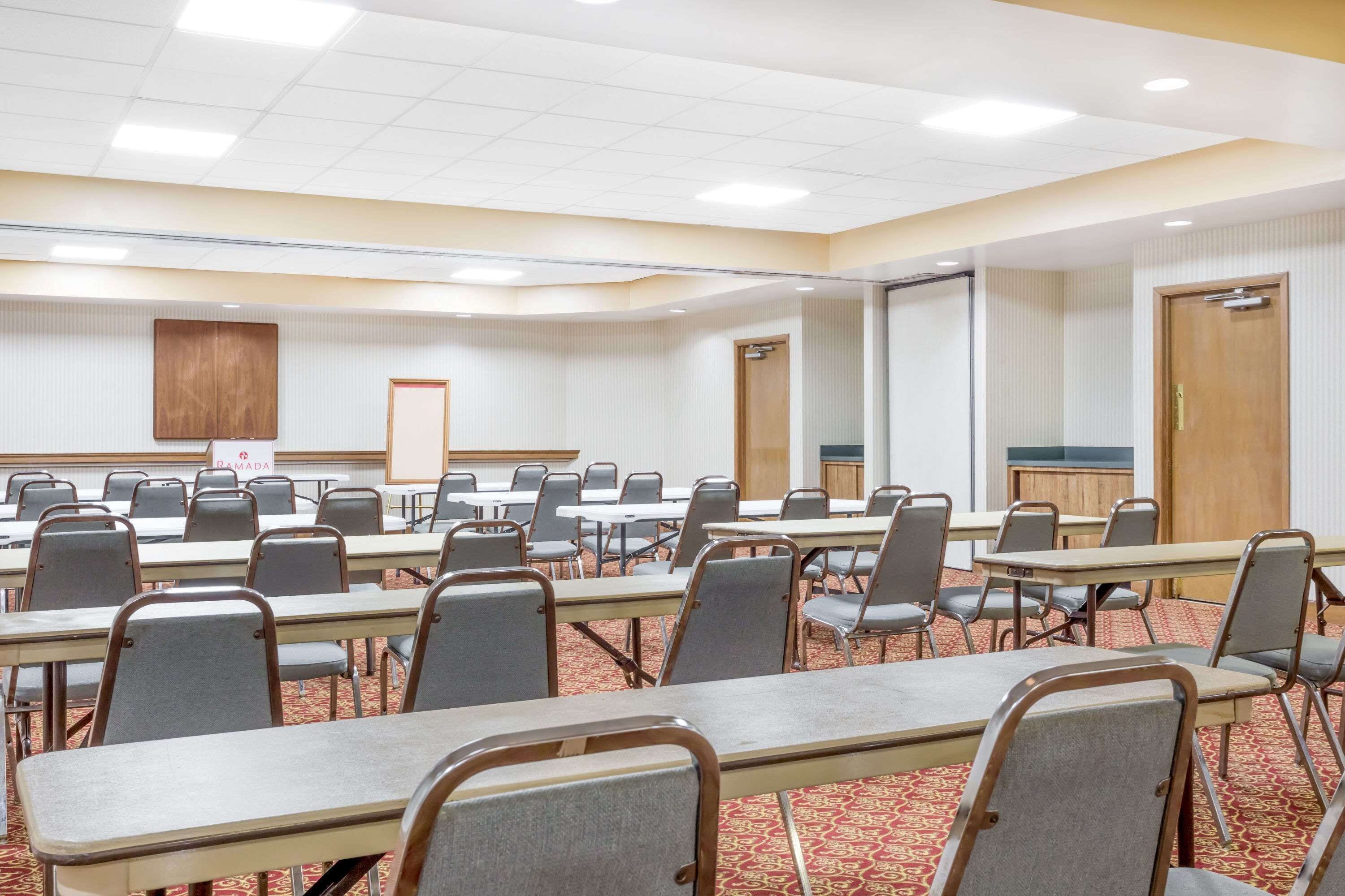 Un salón de conferencias con varias mesas y sillas, una pizarra y un armario de madera.