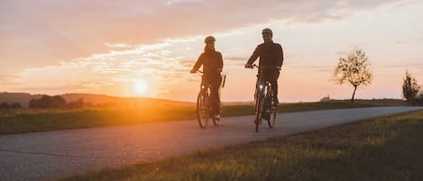 Dos personas andando en bicicleta por una carretera al atardecer.