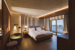 Una habitación de hotel moderna con una cama grande, una ba ñera y un balcón con vistas a la ciudad.