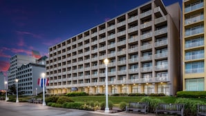 A multi-story hotel with balconies, a flag, and a well-maintained lawn.