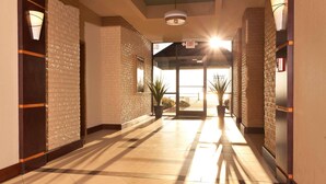 A hotel lobby with a brick wall, a tiled floor, and a glass door leading outside.