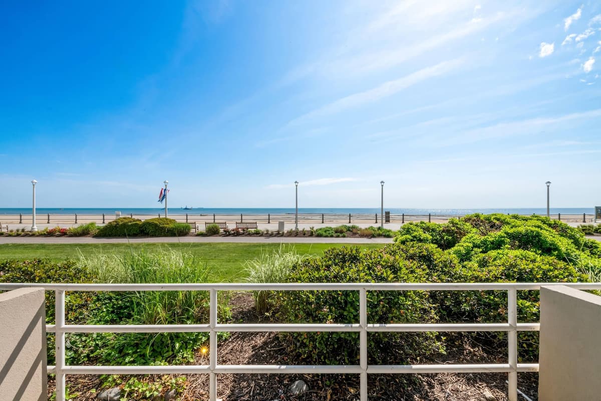 Une vue sur la côte, avec une balustrade blanche, de la verdure et un ciel dégagé.