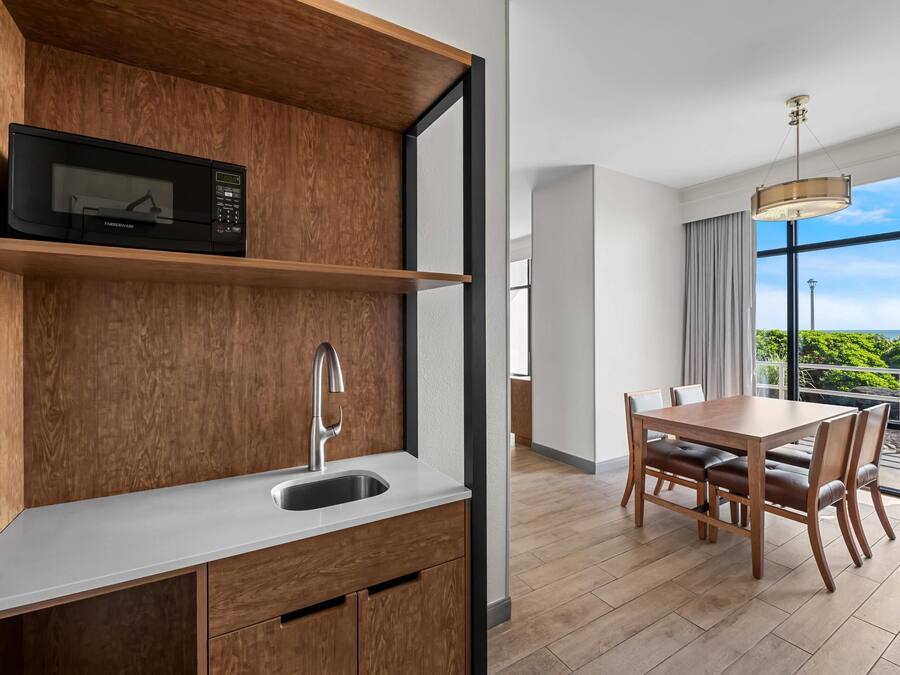 Una cocina moderna con microondas integrado, pileta y muebles de madera.