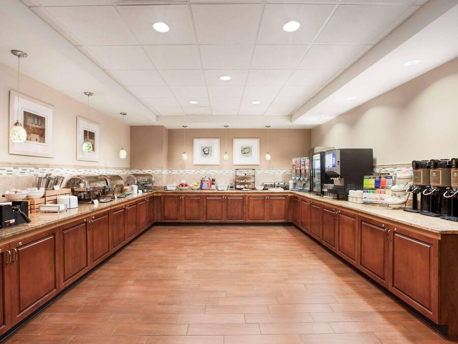 Cozinha espaçosa com armários de madeira, bancada comprida e diversos eletrodomésticos.