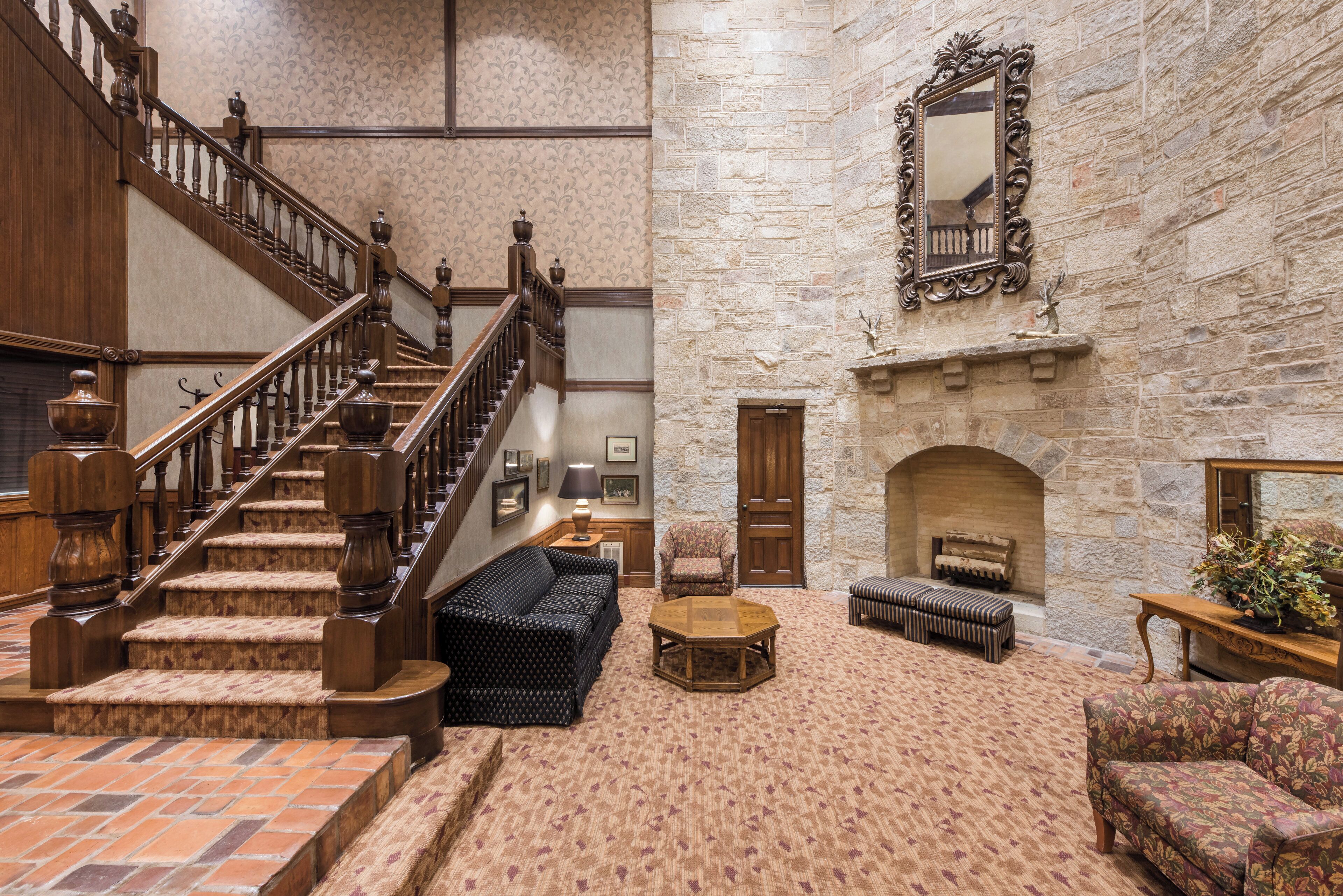 Un hall d’entrée spacieux avec un grand escalier, une cheminée et des coins salon confortables.