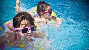 Zwei Personen in einem Schwimmbecken mit bunten Schwimmreifen.