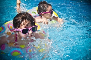 Dos personas en una piscina con aros coloridos inflables.