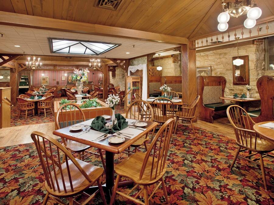 Un restaurant avec des meubles en bois, une moquette à motifs floraux et un plafond haut doté d’une verrière.