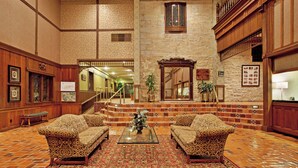 Eine Lobby mit einer imposanten Treppe, zwei gestreiften Sofas, einem Glastisch und einem großen Spiegel.
