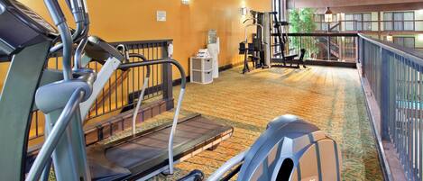 Une salle de sport équipée de matériel d’exercice, avec une horloge et un distributeur d’eau.
