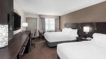 A hotel room with a bed, a desk, a TV, and a bathroom.