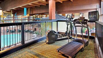 A gym area with exercise equipment, a pool, and a view of the outside.