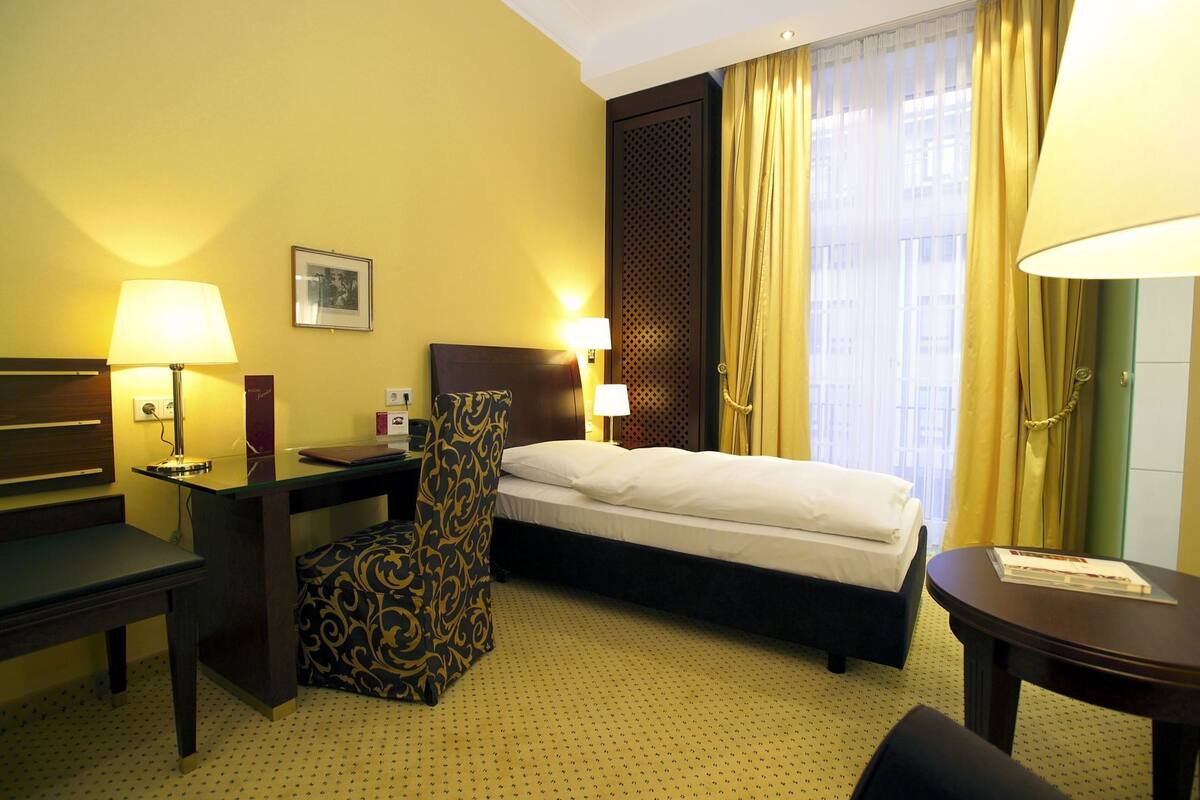 Een hotelkamer met een bed, bureau, stoel en een klein tafeltje.
