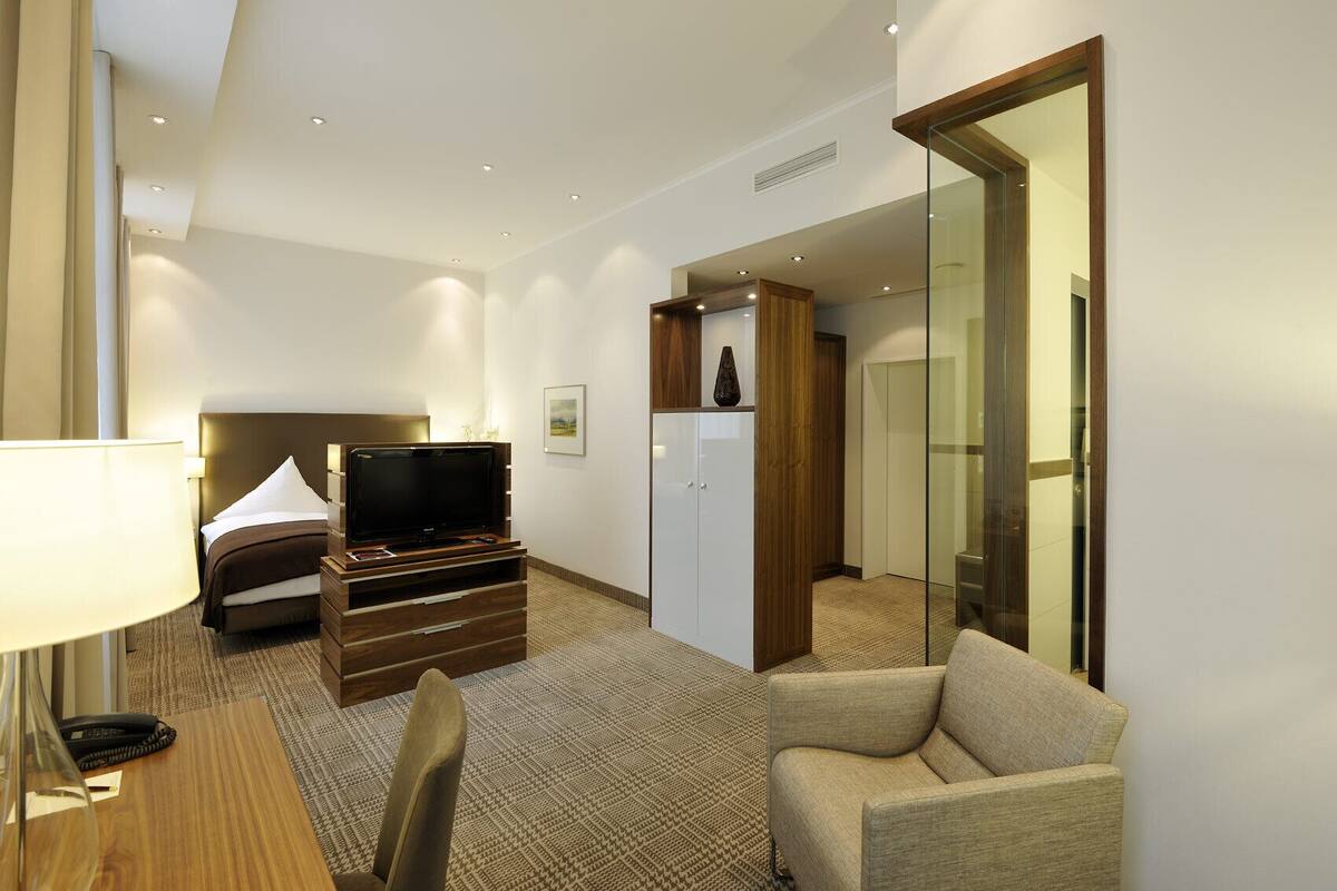 Een hotelkamer met een bed, een televisie, een bureau met lamp, een stoel en een kledingkast.