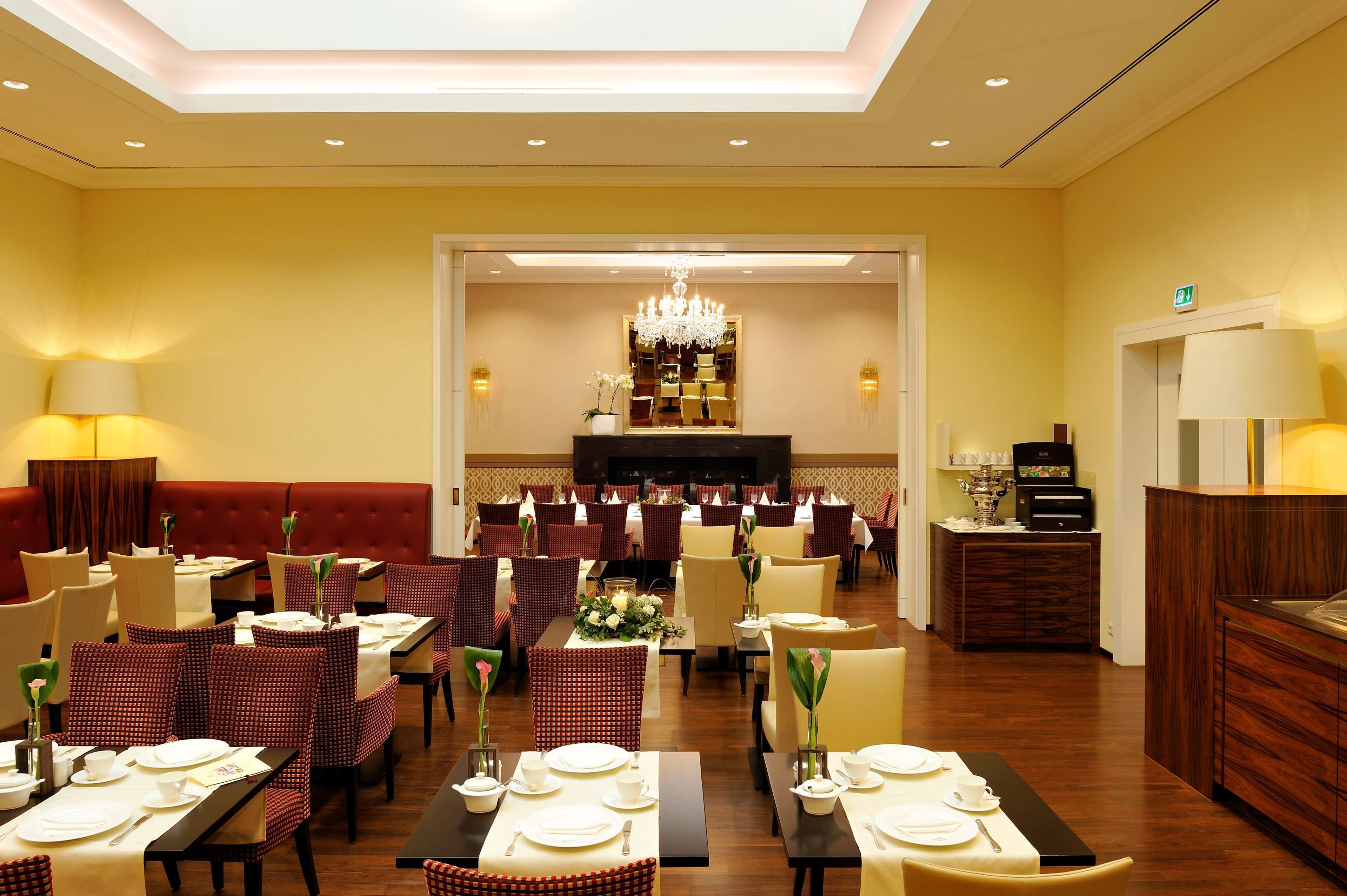 Ein Hotelrestaurant mit gedeckten Tischen, einer Rezeption und einer Kristallleuchtre.