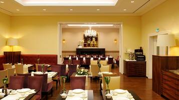 Ein Hotelrestaurant mit gedeckten Tischen, einer Rezeption und einer Kristallleuchtre.