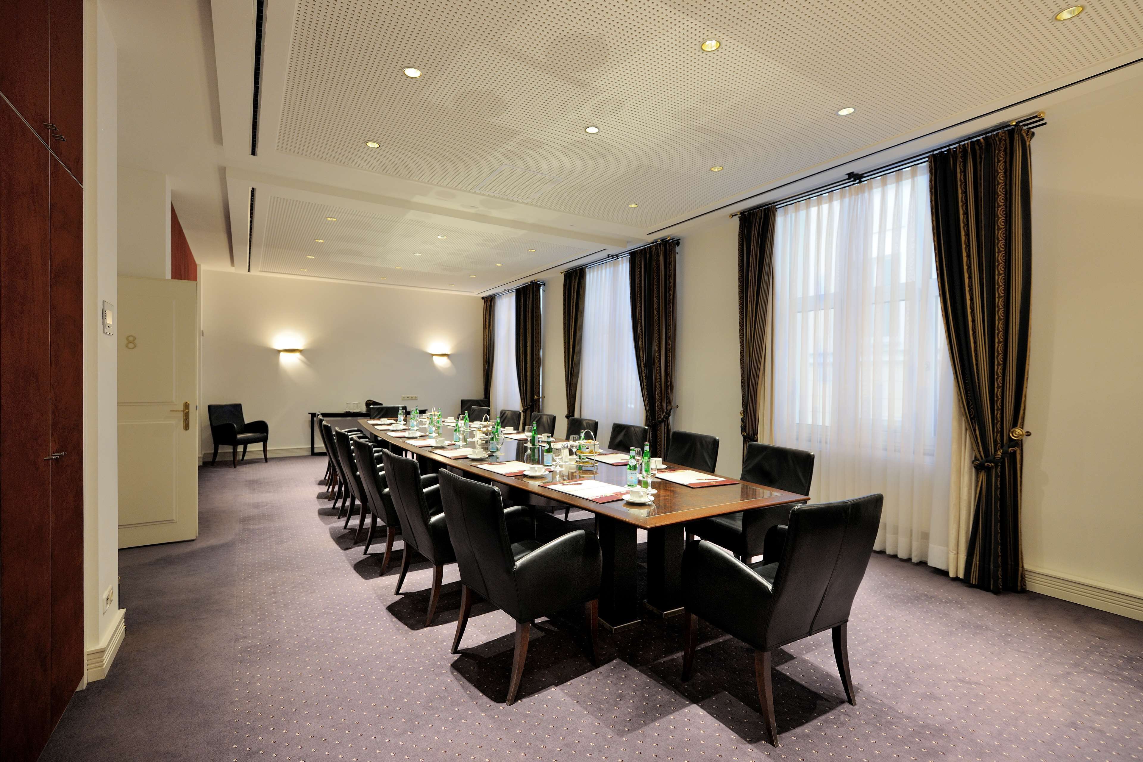 A conference room with a long table, chairs, and a door leading to another room.