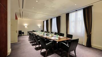A conference room with a long table, chairs, and a door leading to another room.