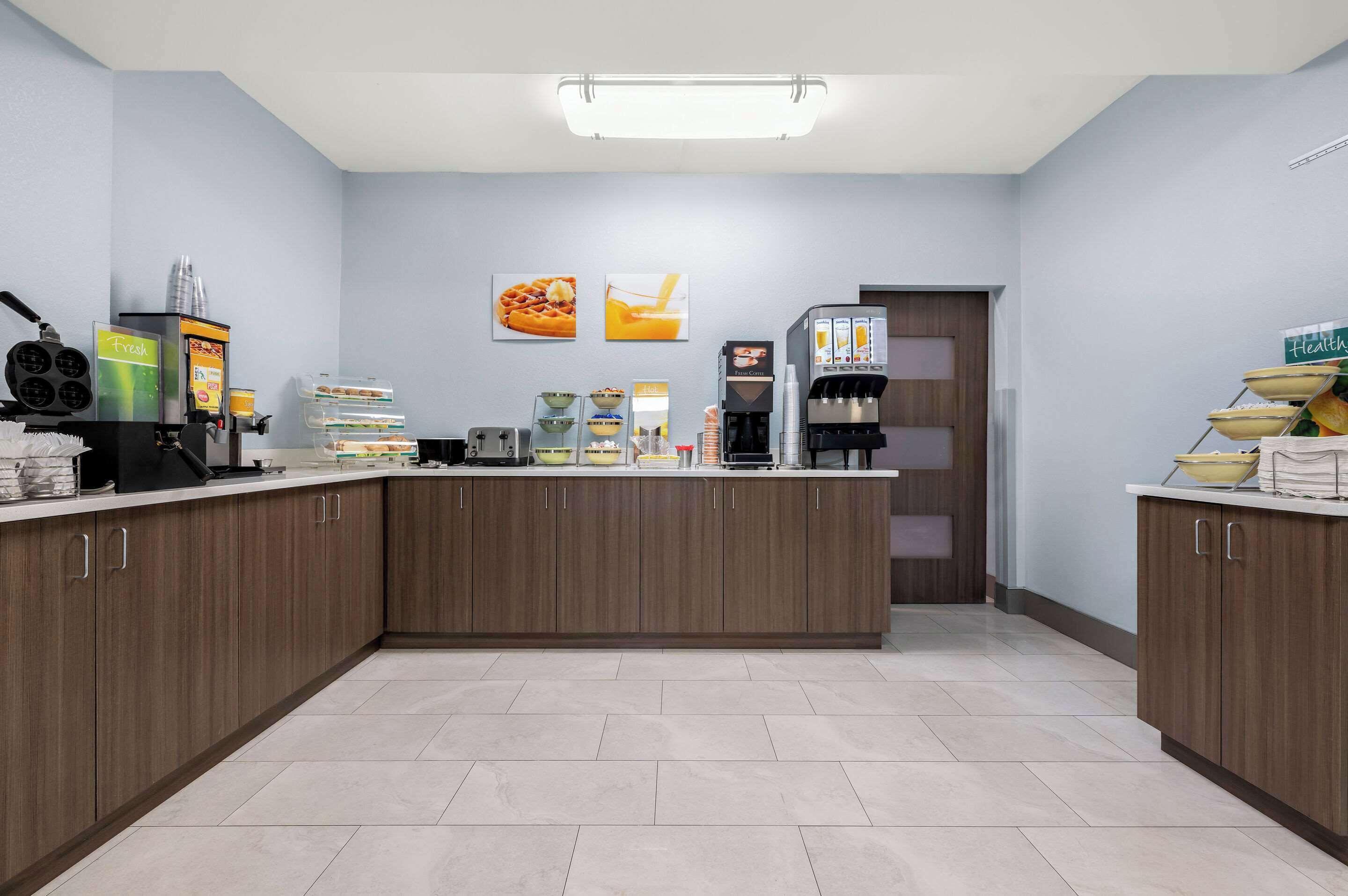 A modern kitchen area with a central island, various appliances, and a breakfast bar.