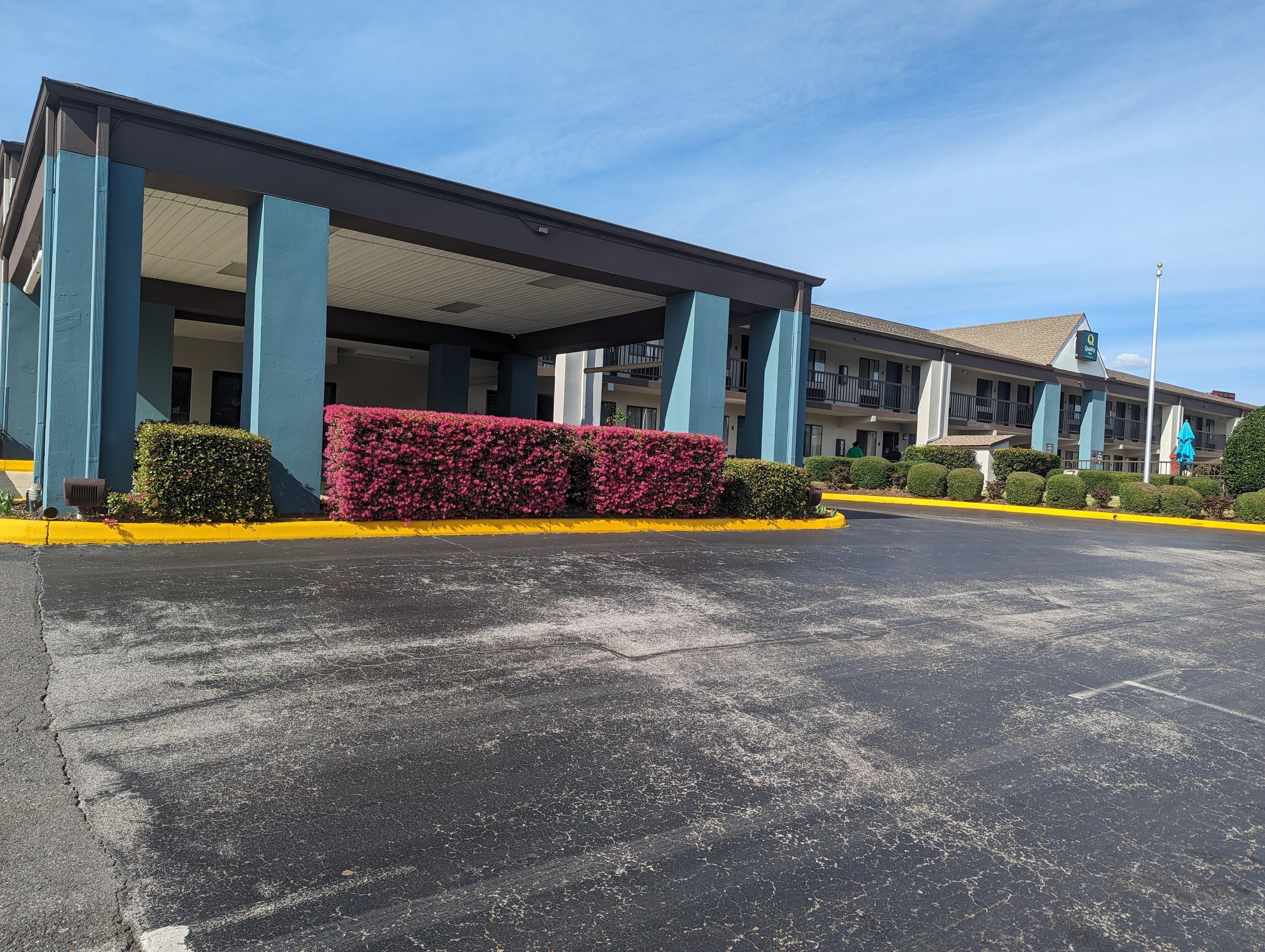 A hotel with a covered entrance, large columns, and a parking lot.