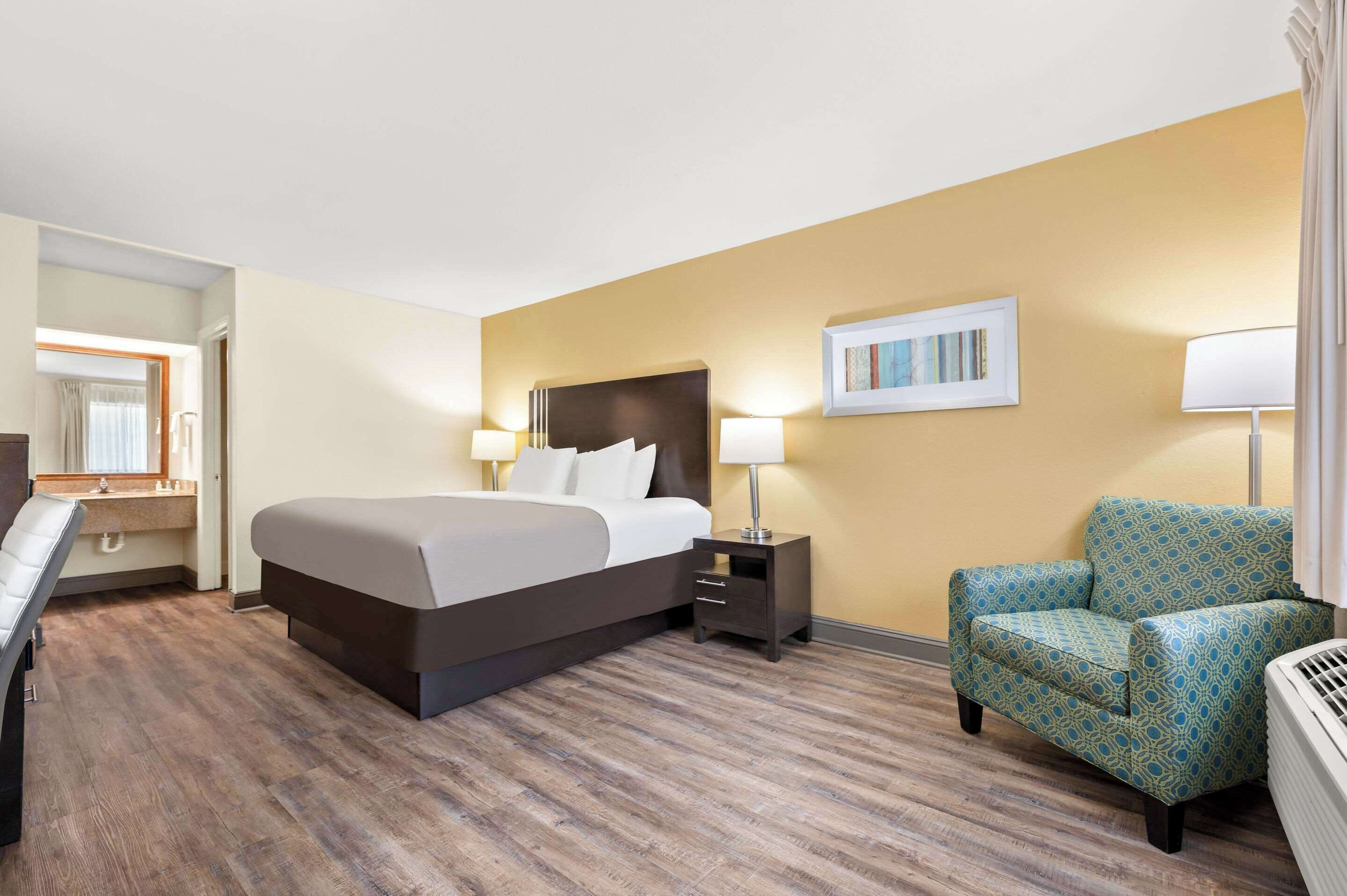 Una camera d'albergo con un letto grande, comodini, una sedia e uno specchio.