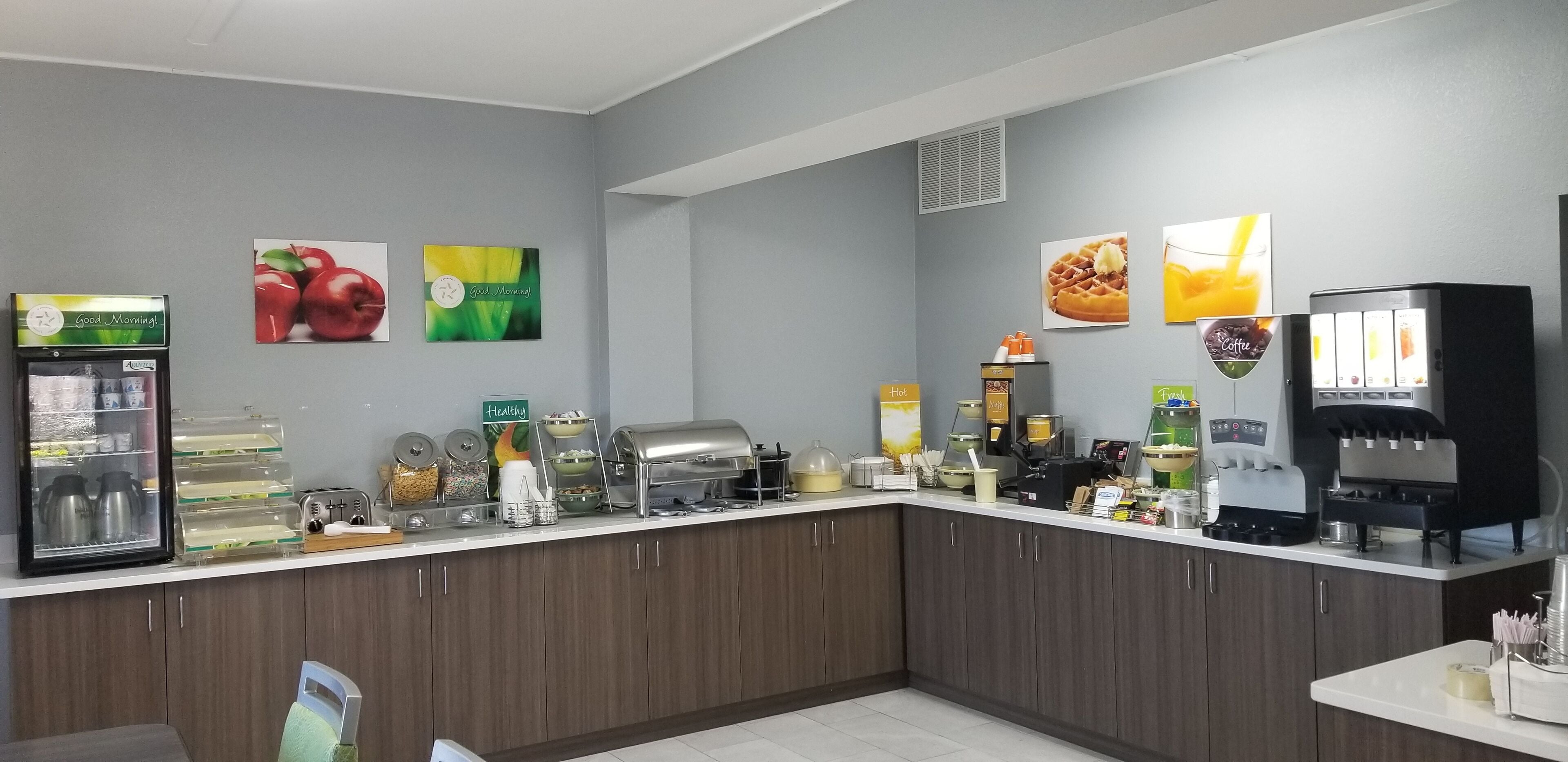 A breakfast bar with a refrigerator, coffee machines, and various food containers.