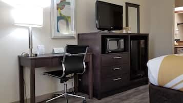 Habitación de hotel con escritorio, silla, televisión, microondas y cama.