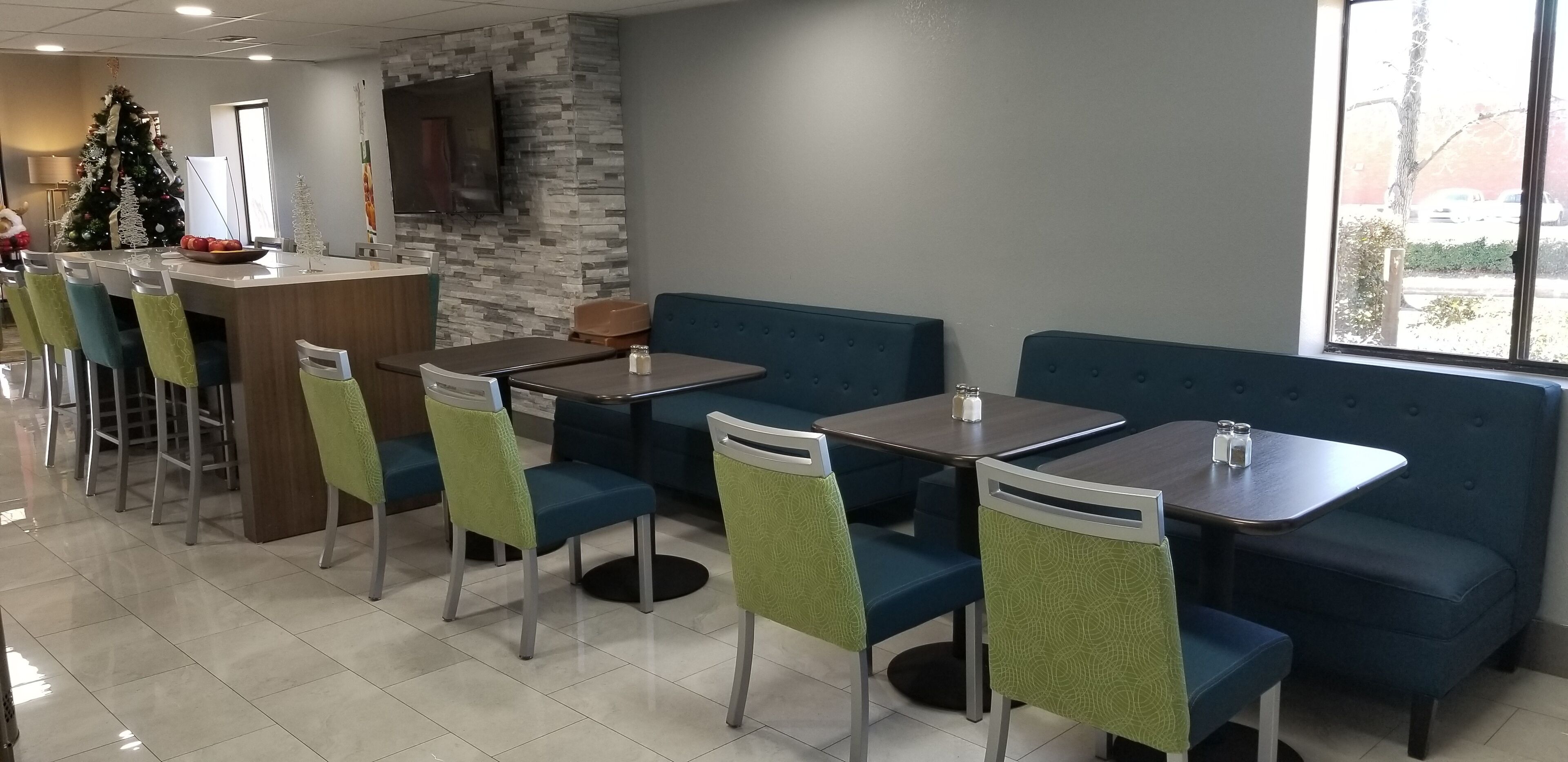Un restaurant avec des banquettes et des tables, un sapin de Noël et un mur en pierre.