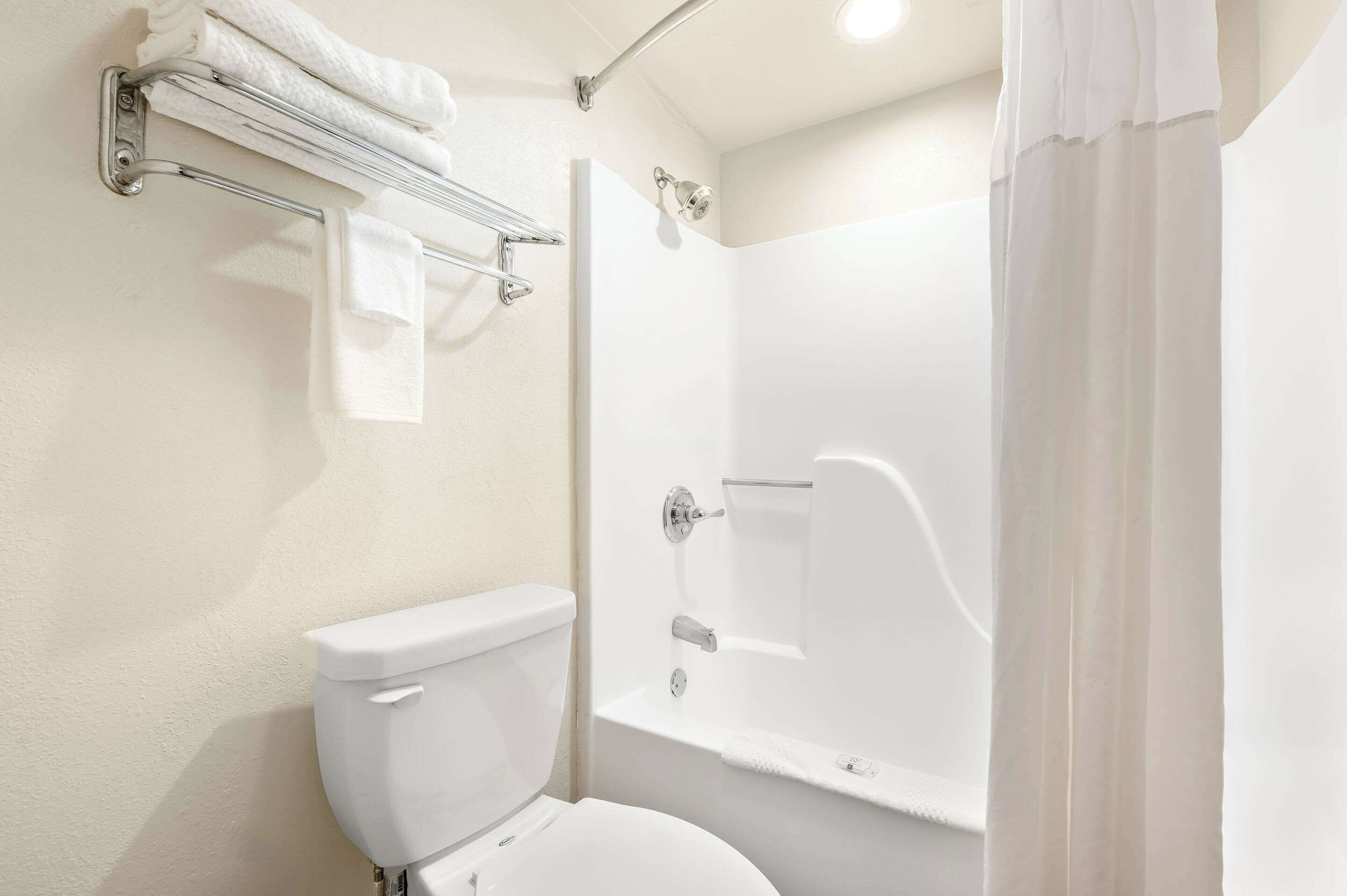 Un bagno con il water, una doccia con porta in vetro e un portaservizi con asciugamani piegati.