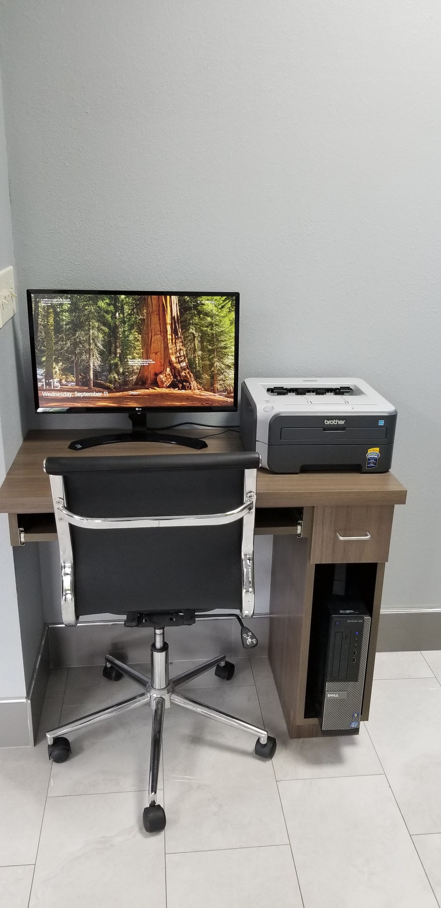 A desk with a computer monitor, printer, and office chair.