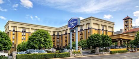 Un hotel Hampton Inn con un cartel llamativo, varios pisos y una torre.