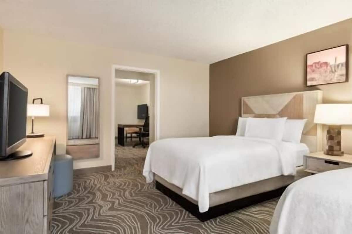 A hotel room with a bed, a desk, a television, and a chair.