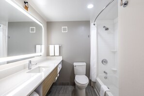 A modern bathroom with a white sink, vanity, toilet, and bathtub.
