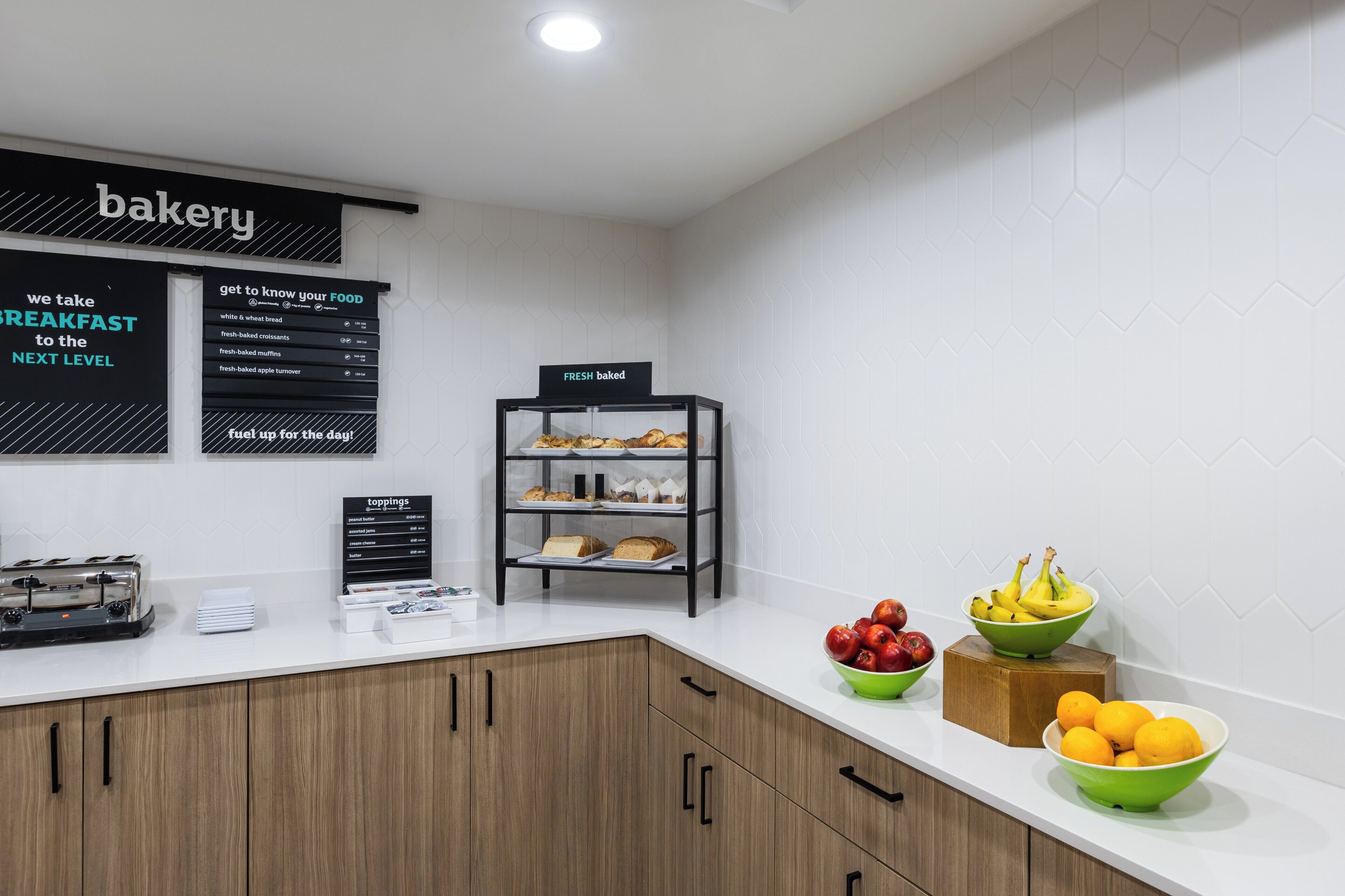 Eine Theke in einer Bäckerei mit Speisekarte, einer Auswahl an Backwaren und Schalen mit frischem Obst.